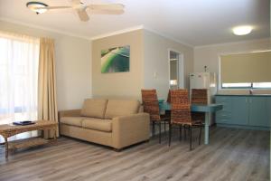 a living room with a couch and a table at Aqua Villa Holiday Apartments in Coffs Harbour