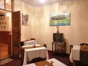 a dining room with two tables and a tv at Huaytusive Inn Hotel in Puno