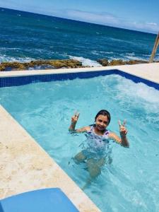uma mulher numa piscina perto do oceano em Discovery Inn & Suites at 681 Ocean Drive em Arecibo