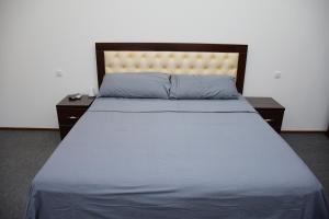 un letto con lenzuola blu, 2 comodini e sidx sidx sidx di Nurziyo Guest House a Tashkent