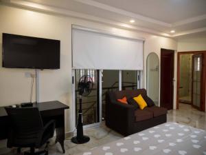 a living room with a couch and a desk and a television at Zion Place in Ikeja
