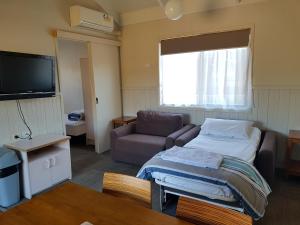 um quarto com uma cama, um sofá e uma televisão em Canberra Carotel Motel em Camberra
