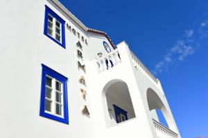 a white building with blue windows against a blue sky at Armata Boutique Hotel in Spetses