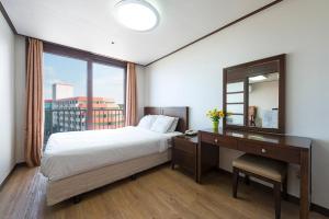 a bedroom with a bed and a desk with a mirror at Hyundai Soo Resort Sokcho in Sokcho +18 photos
