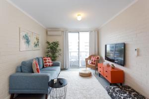 a living room with a blue couch and a tv at Stay Okay Central - Fremantle in Fremantle