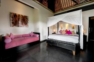 a bedroom with a large bed and a couch at Villa Rumah Lotus in Payangan