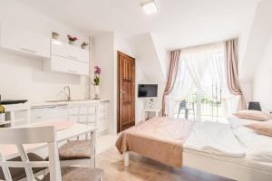 a white bedroom with a bed and a kitchen at Willa Arkadia w Pucku in Puck