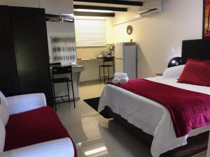 a bedroom with a large bed and a kitchen at Francor Guesthouse in Pretoria