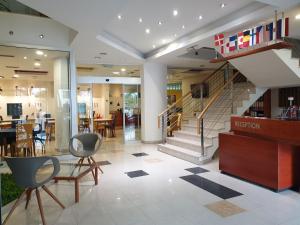 een lobby met een trap, stoelen en een tafel bij Hotel Hecco in Sarajevo