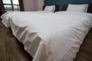 uma grande cama branca com lençóis e almofadas brancos em Hyundai Elliot Hotel and Resort em Pyeongchang