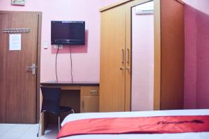 a bedroom with a bed and a desk and a tv at RedDoorz at Pettarani Square Makassar in Makassar