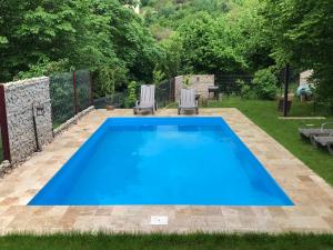 a large blue swimming pool in a yard with two chairs at Calea Poienii Penthouse in Braşov