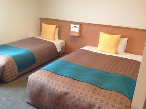 Hotel 1-2-3 Shimada في Shimada: غرفة فندق بسريرين باللونين الأصفر والأزرق