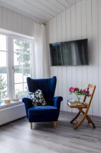 einen blauen Stuhl im Wohnzimmer mit einem TV in der Unterkunft Haus Kilstrand in Tämta