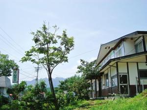 budynek na wzgórzu z drzewem obok niego w obiekcie Togakushi- Kogen Minshuku Rindo w mieście Nagano