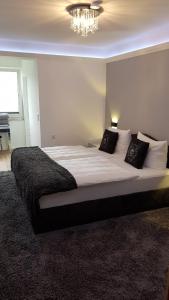 um quarto com uma cama grande com lençóis brancos e almofadas em Pension Gockels-Auszeit em Bad Wildungen