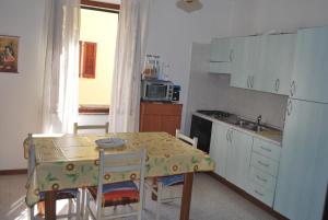 małą kuchnię ze stołem, stołem i krzesłami w obiekcie Stella Marina w mieście Stintino