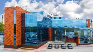 a large glass building with cars parked in a parking lot at F911 Яхт Клуб Отель in Yekaterinburg