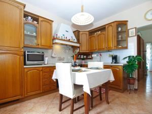 uma cozinha com armários de madeira e uma mesa com cadeiras brancas em Apartment Mile 1872 em Fažana