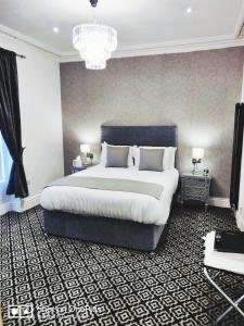 a bedroom with a large bed and a chandelier at Serendipity House in Derry Londonderry