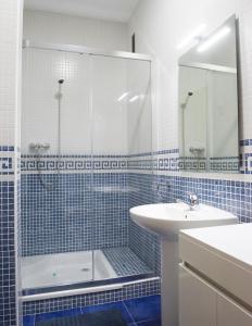 y baño de azulejos azules con ducha y lavamanos. en CASA DEL CIRCULO MERCANTIL, en Villanueva del Arzobispo