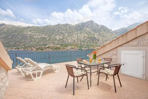 eine Terrasse mit einem Tisch, Stühlen und Bergen in der Unterkunft Apartments Jankovic in Kotor
