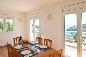 a dining room with a table and chairs and windows at Montgo 1 in L'Escala