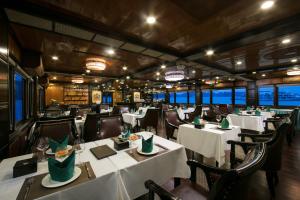 uma sala de jantar com mesas e cadeiras brancas em La Regina Royal Cruise em Ha Long