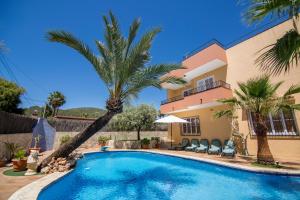 a swimming pool in front of a house with palm trees at Villa Palmera in Ibiza Town