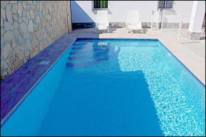 - une grande piscine bleue avec 2 chaises dans l'établissement Chalet Ermita, à Conil de la Frontera