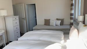 biała sypialnia z 2 łóżkami i lustrem w obiekcie Pension Richter w mieście Nienhagen