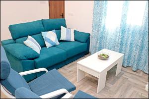 a living room with a blue couch and a table at Chalet Ermita in Conil de la Frontera