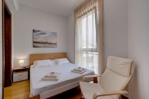 a bedroom with a bed and a chair and a window at SunRay in Tivat