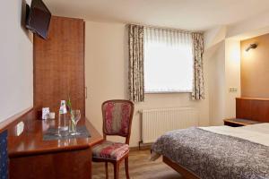 ein Hotelzimmer mit einem Schreibtisch und einem Bett in der Unterkunft Hotel Eisenbahn in Karlstadt