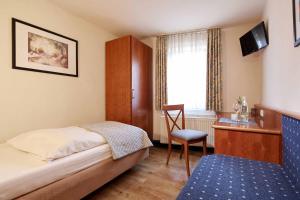 Schlafzimmer mit einem Bett, einem Schreibtisch und einem Stuhl in der Unterkunft Hotel Eisenbahn in Karlstadt