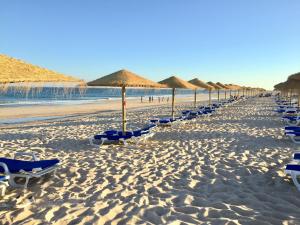 a row of beach chairs and umbrellas on a beach at Quinta da Lua in Tavira