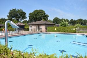 een groot blauw zwembad in een tuin bij 6 pers. Veluwevilla in Voorthuizen