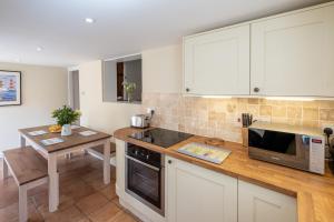 cocina con armarios blancos y encimera de madera en Little Tern Cottage, en Aldeburgh