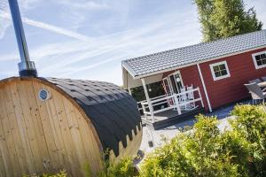 a red house with a large wooden barrel in front of it at 6 pers. Veluwelounge + Wellness in Voorthuizen