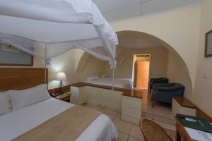 a hotel room with a bed and a bed and a chair at Sunbird Nkopola in Chipoka