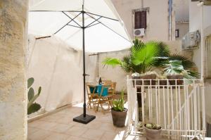 La terrazza di Archimede- Ortigia Holidays في سيراكوزا: وجود مظلة بيضاء تجلس على فناء به نباتات