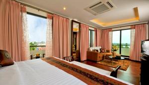a bedroom with a large bed and a living room at Salana Boutique Hotel in Vientiane