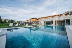 a swimming pool with blue water in front of a building at Sporthotel Floralpina in Alpe di Siusi