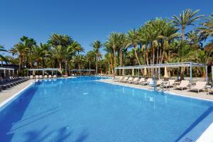 
a beach with a pool, chairs, and a pool table at Hotel Riu Palace Oasis in Maspalomas
