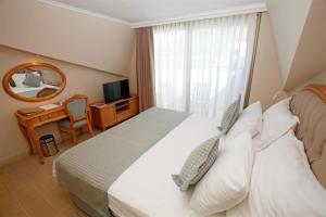 a bedroom with a bed and a desk and a mirror at Hotel Aqua in Marmaris