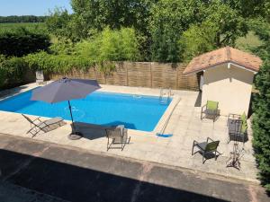 Una sombrilla y sillas junto a una piscina. en La Maison des Brandes, en Eynesse 4 fotos más