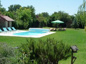una piscina en un patio con sillas y sombrilla en Le Verger du Sausset en Beaune