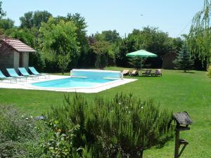 a pool in a yard with chairs and an umbrella at Le Verger du Sausset in Beaune