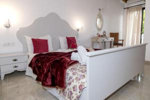 a white bedroom with a large white bed with red pillows at Studio Galatia in Kamilari