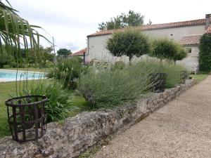 een steunmuur met planten naast een zwembad bij Du Côté de l'Ombrière in Geay
